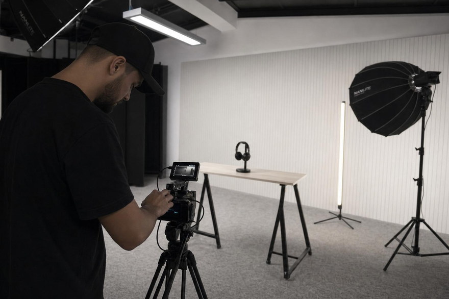 Camera operator adjusting the camera on set, with the product table and lights ready.